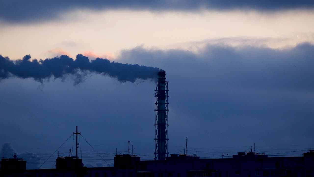浓烟从高高的烟囱里冒出来，映衬着黑暗的天空。工业景观。视频下载