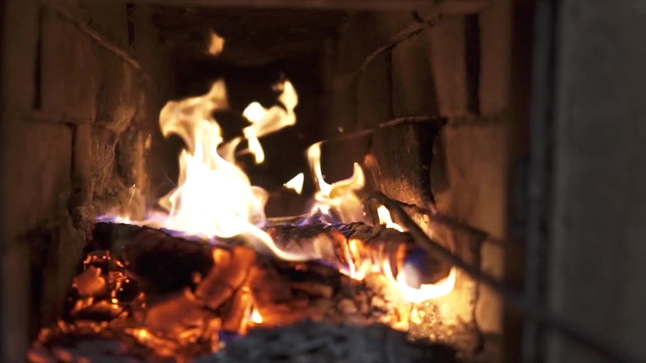 一个人在整理壁炉里的木柴。火花飞舞视频下载