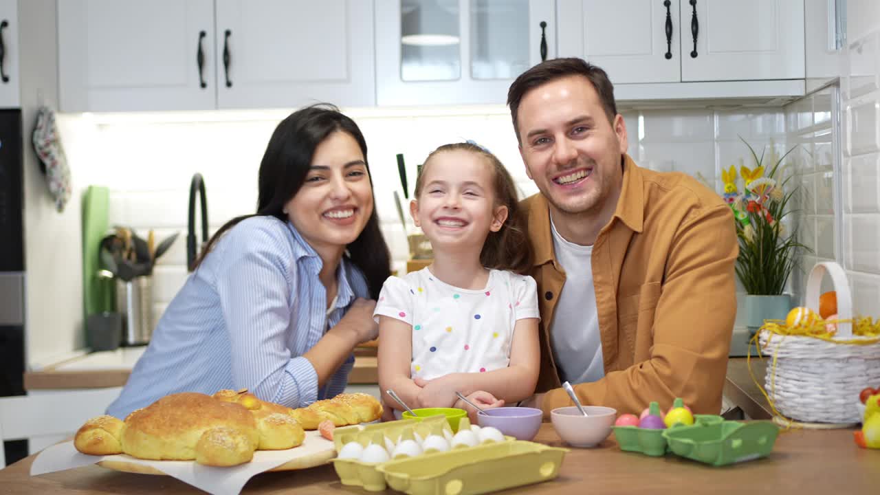 一个年轻的白人家庭的肖像，在厨房里给复活节彩蛋上色视频下载