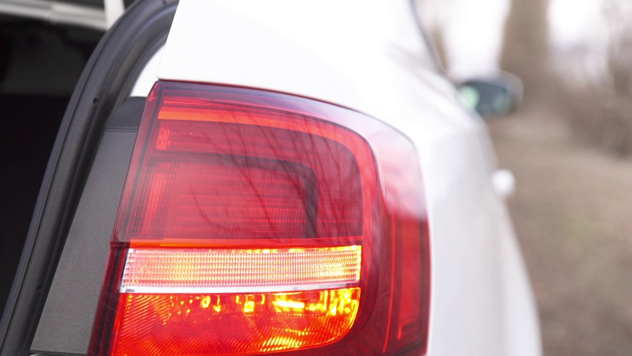 一辆白色汽车前灯的特写，转向灯在闪烁。汽车报警器响了。安全的信号。视频下载