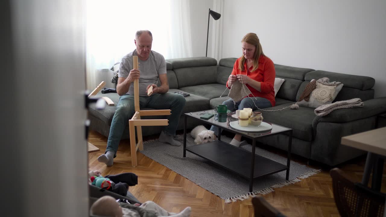 老妇人在织围巾，她丈夫在客厅里修椅子视频下载