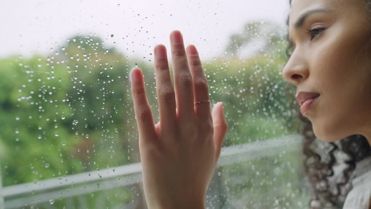 悲伤，女人和思考与手在窗户为雨天，沮丧或错误在室内的家。心理健康或焦虑的年轻女性在家中向外看或触摸玻璃的特写视频下载