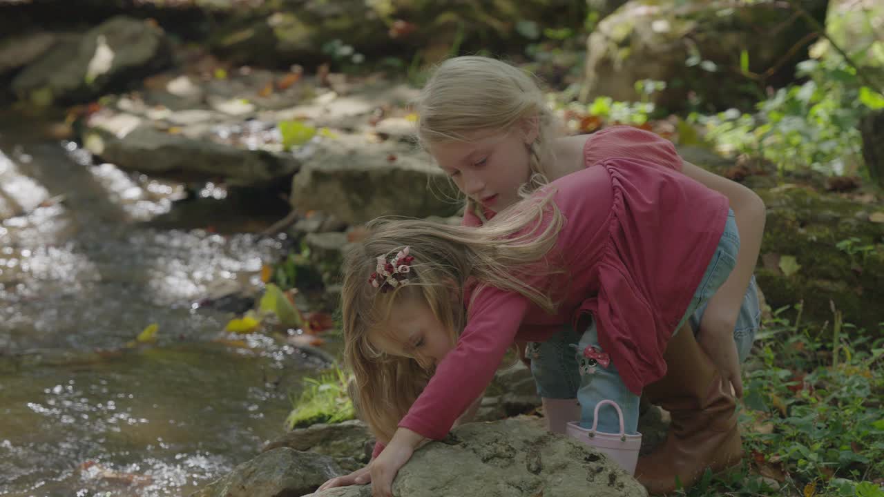 好奇的女孩在美国肯塔基州Goshen附近的小溪/岩石下寻找视频下载