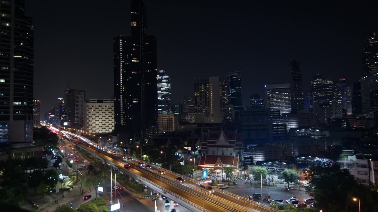 一个繁忙的城市在夜晚充满活力，在摩天大楼的灯光下，突出了稳定的交通流量。曼谷泰国视频下载