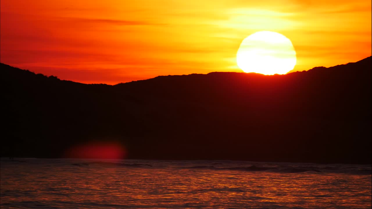夕阳落在多石的海岸上。时间流逝视频下载