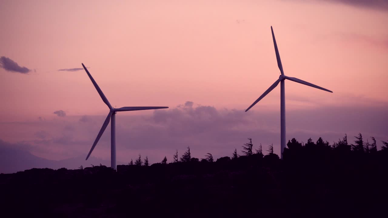 风力涡轮机对着夕阳的天空。视频下载