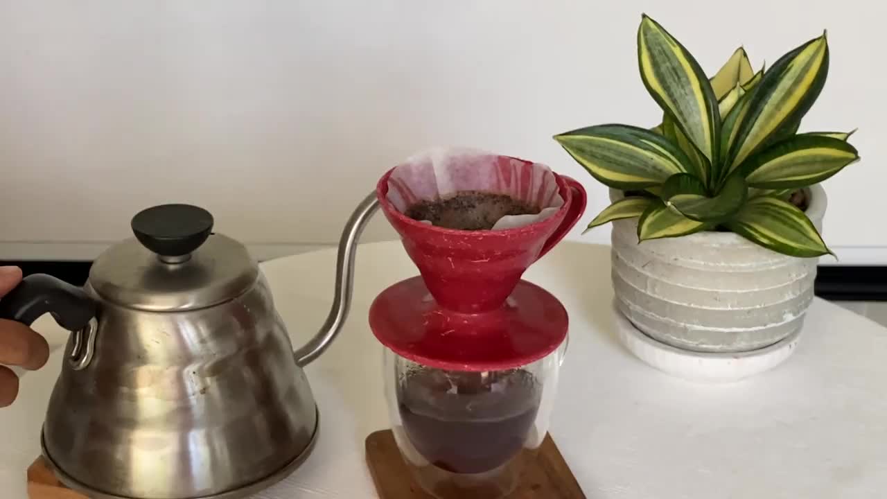 亚洲妇女用过滤器往咖啡粉上倒水视频下载