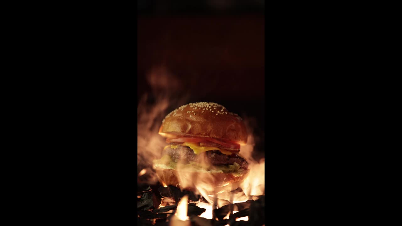美味的汉堡在火上。美味的汉堡配上新鲜的洋葱、西红柿和烤牛排。视频下载