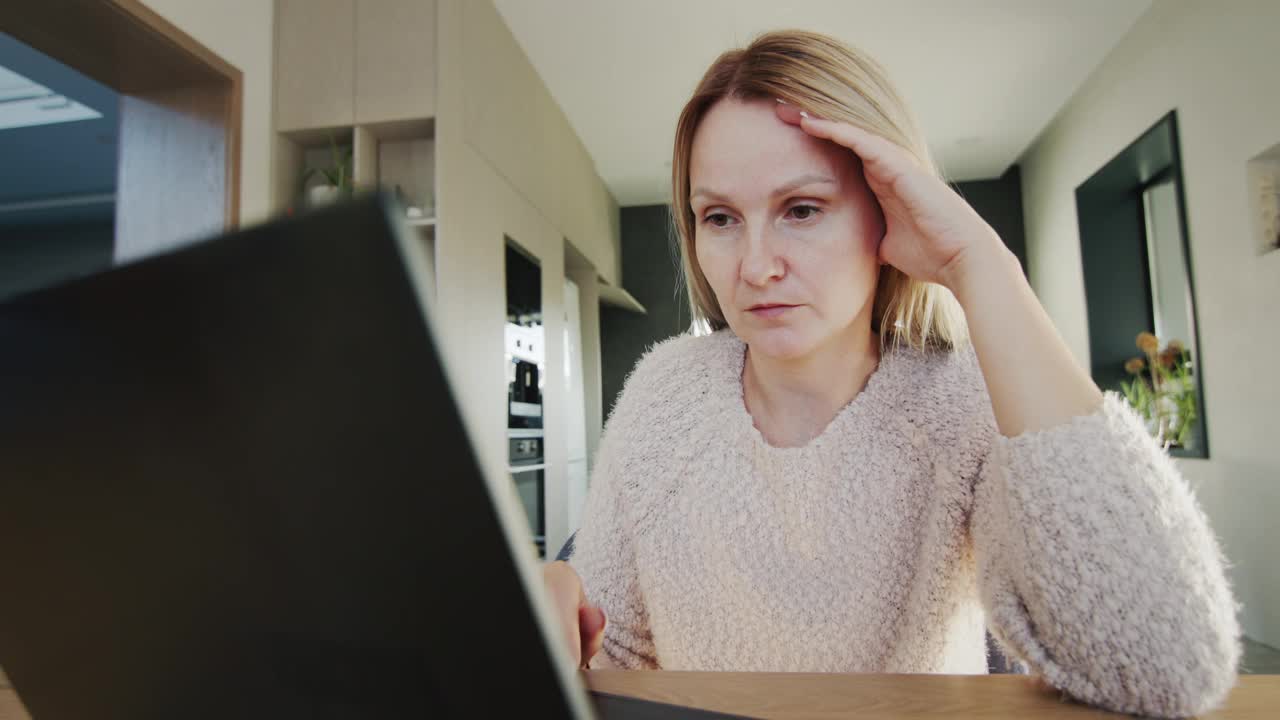 沉思的悲伤的女人坐在笔记本电脑显示器前。广角镜头4k拍摄视频下载