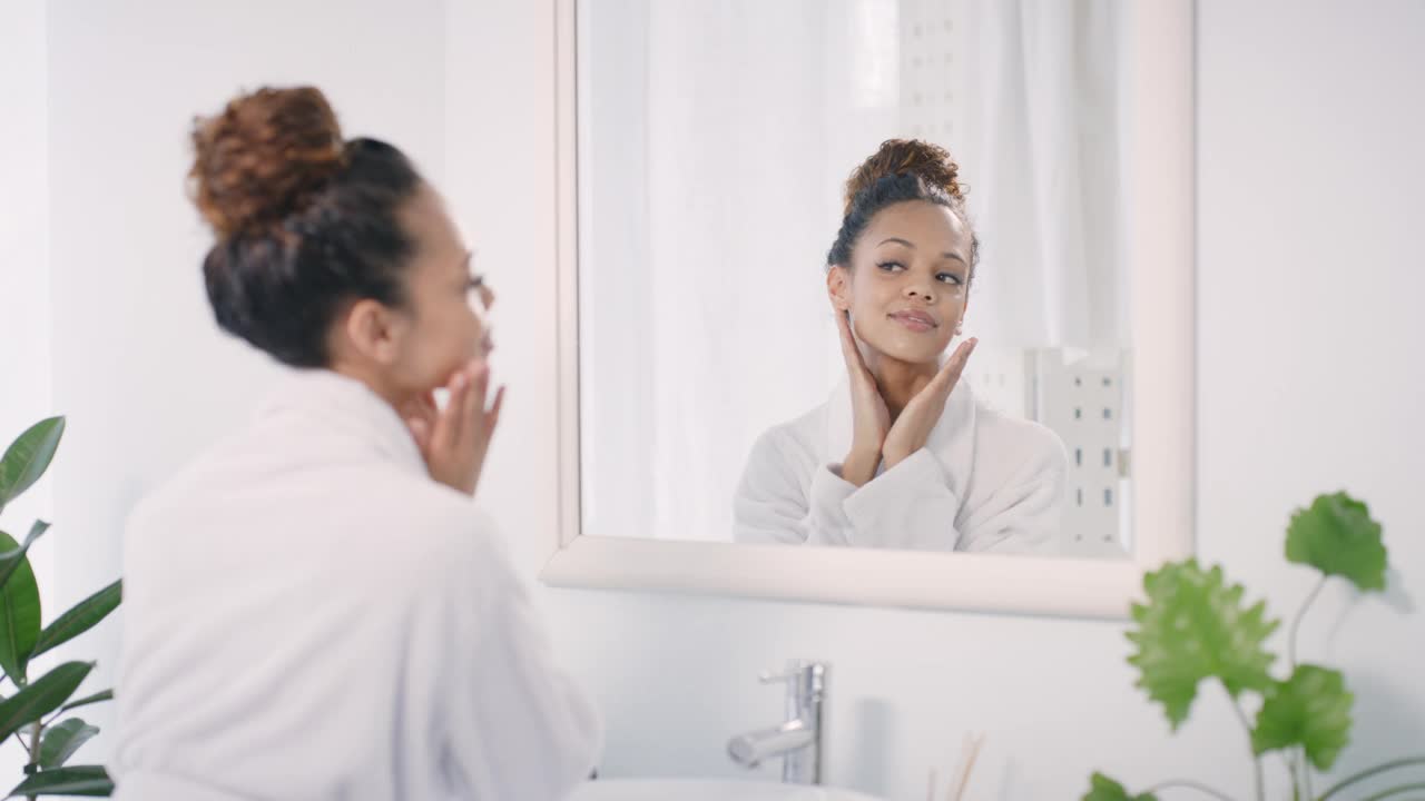 美容、护肤和镜子，镜子里是一个黑人女性早上在浴室例行公事时的样子。美容，健康和豪华与一个有吸引力的年轻女性在她的家皮肤护理视频下载
