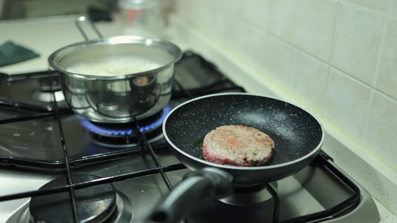 在家庭厨房炉子上的平底锅里煮的汉堡和煮熟的意大利面视频下载