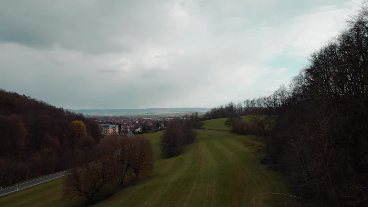 村庄周围环绕着美丽的绿色丘陵景观，日出时色彩斑斓，航拍画面。德国。视频下载