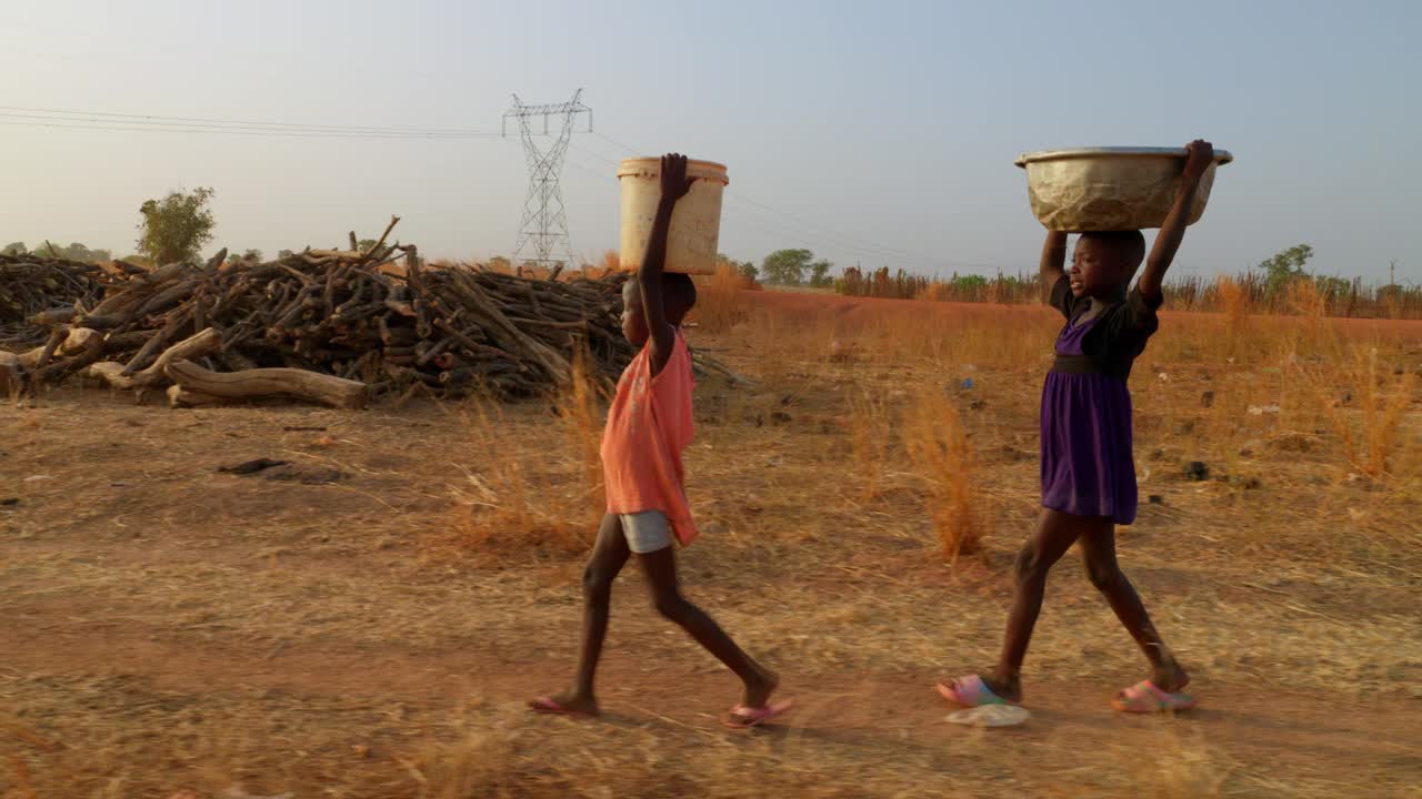 在非洲，几个孩子头顶着水桶，背着一桶纯净水走到非洲偏远的农村视频下载