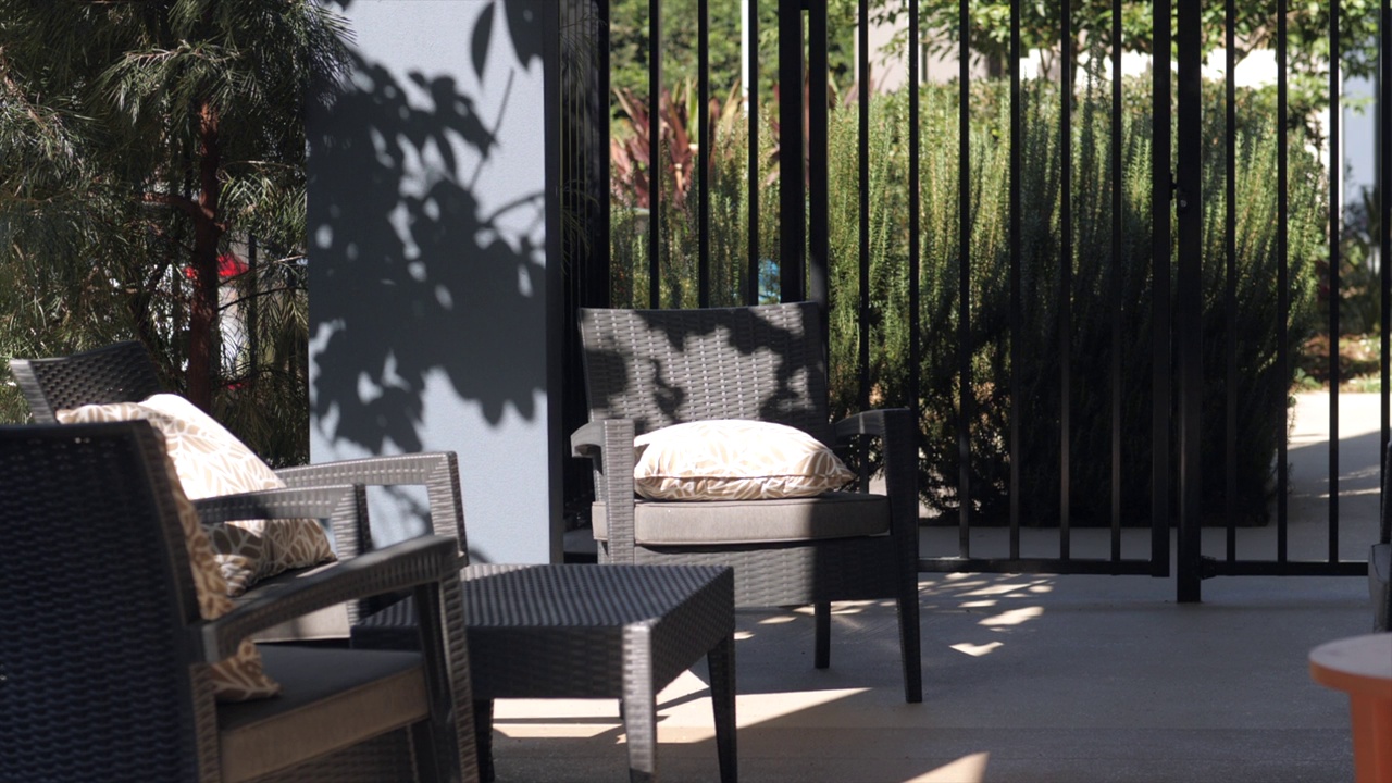 现代户外家具位于受保护的安全露台上，周围环绕着泳池围栏和景观花园，为午后的阳光提供遮阳。视频下载