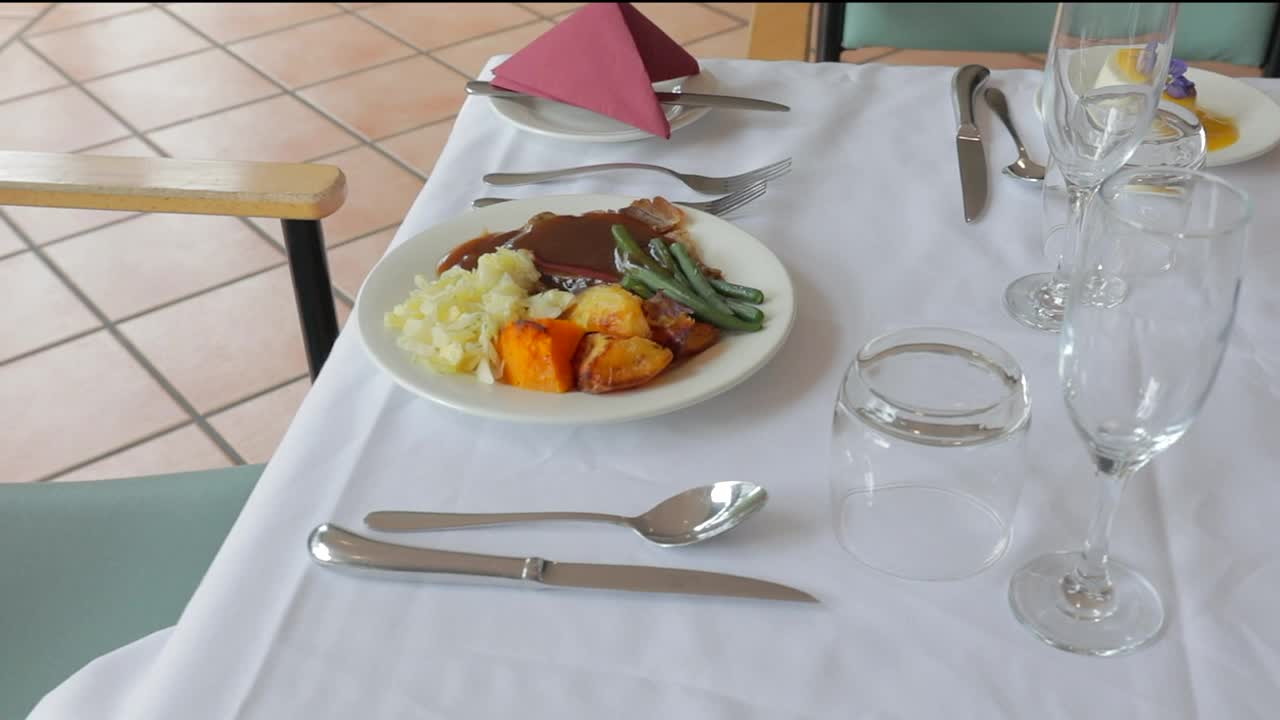 一顿美味的冬季热餐，由烤牛肉和蔬菜组成，在酒店餐厅的单人座位上享用，甜点是意式奶冻和西番莲果酱。视频下载