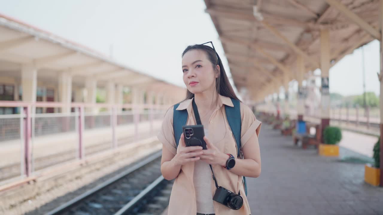 一位女旅客在火车站查看她的智能手机视频下载