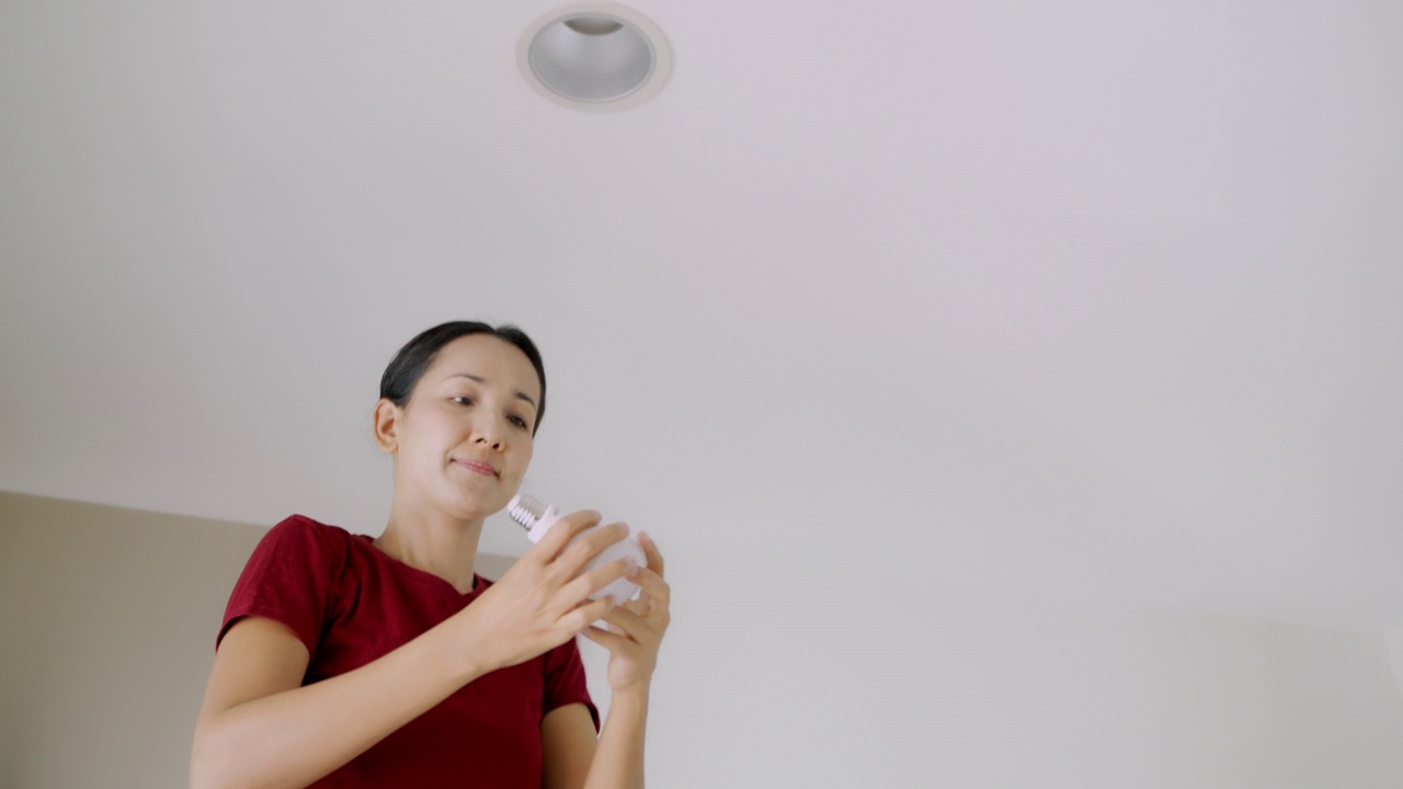 亚洲女人在家里自己换LED灯泡。视频下载