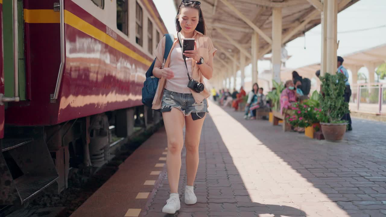 一位女旅客在火车站查看她的智能手机视频下载