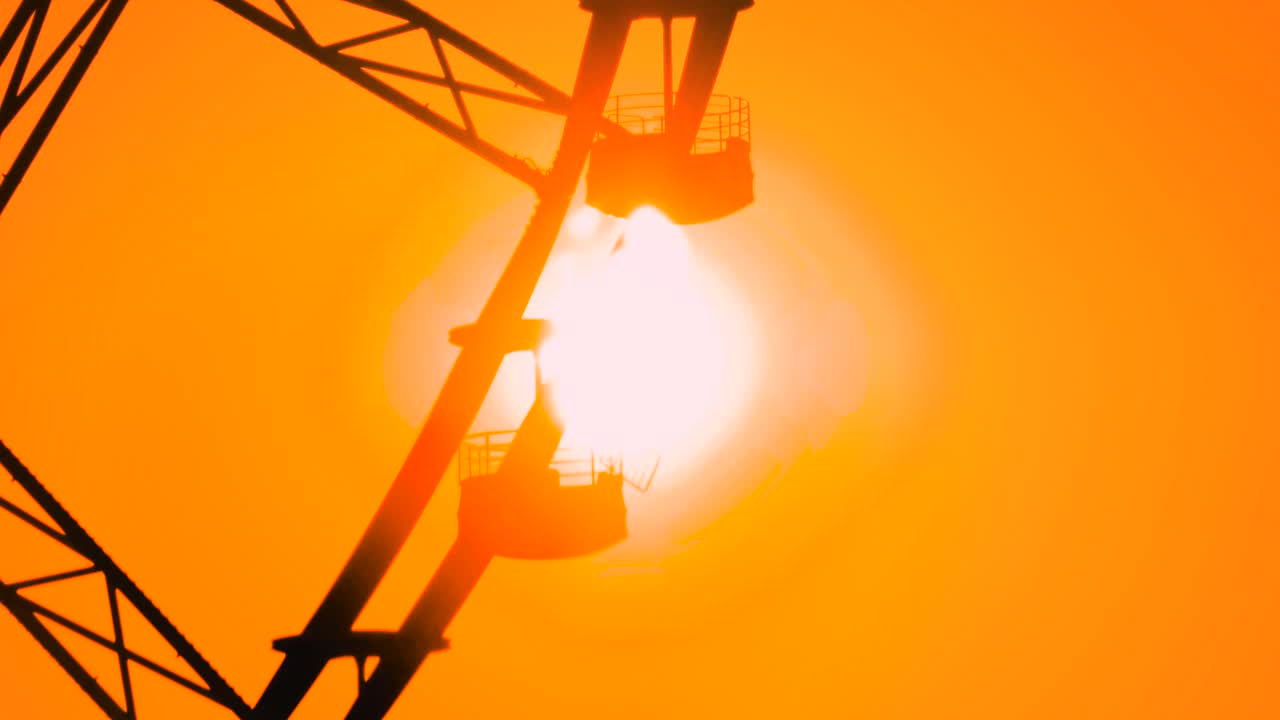 摩天轮的剪影在橘黄色夕阳的映衬下旋转视频下载