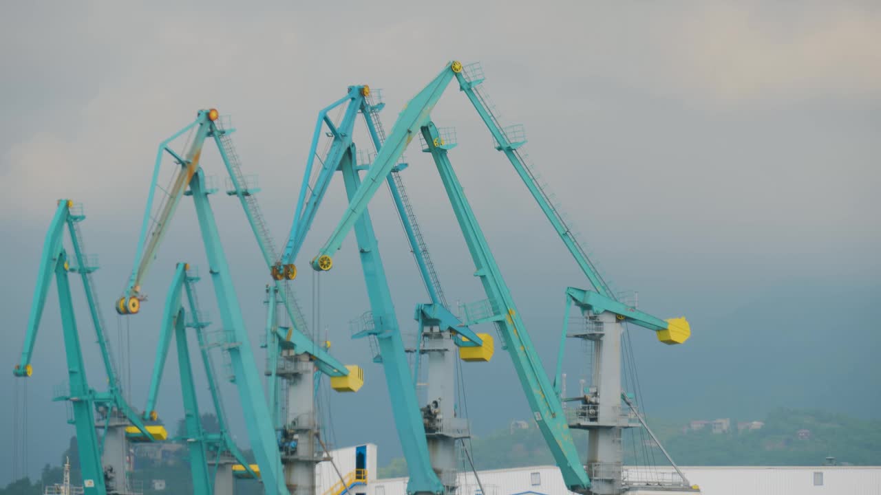几台港口起重机顶着多云的天空在海港工作视频下载