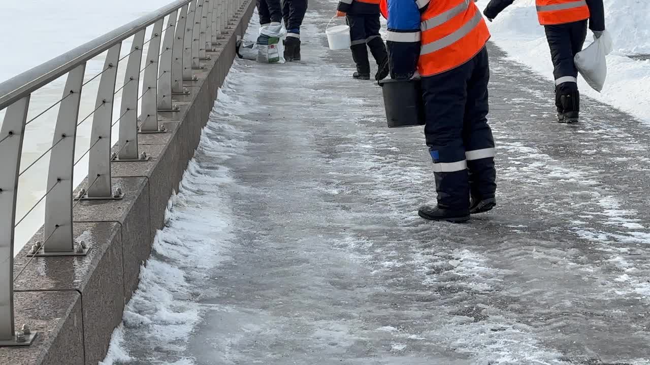 工人们在人行道上撒盐。冬季路面用除冰剂处理，防止路面打滑视频下载