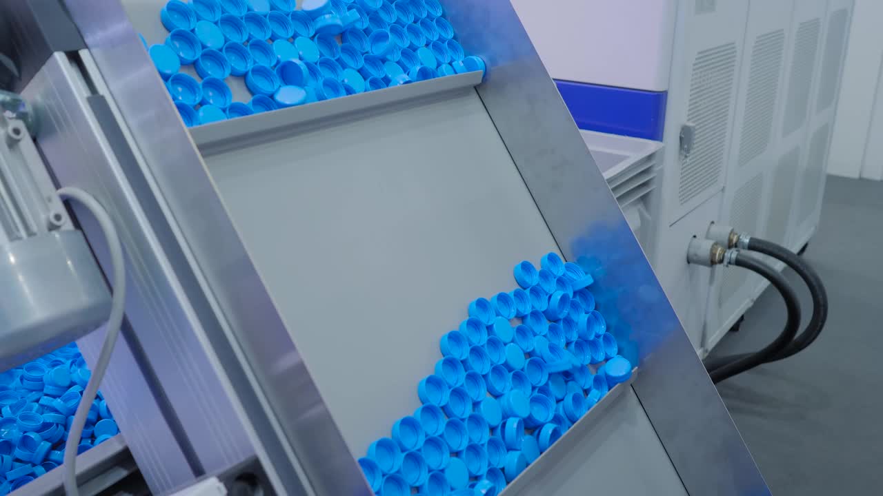 许多蓝色塑料瓶盖在传送带生产线上移动视频下载