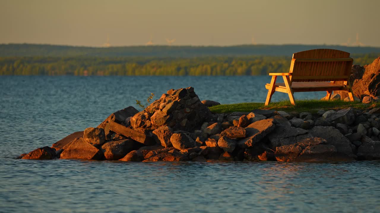 浪漫的空长凳在小船湾的马尼托湖，黄金时间日落黄昏。依偎在宁静的水的宁静魅力。金色的光芒投下迷人的光芒，浪漫的气氛。视频下载