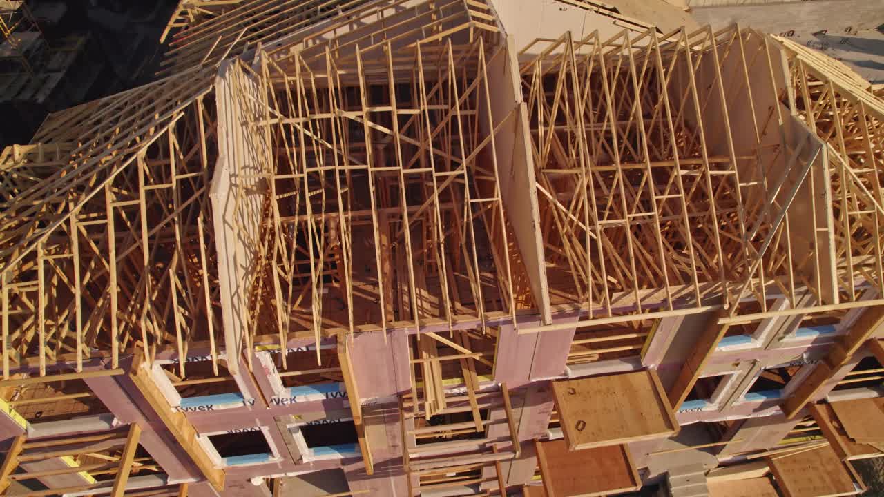 加拿大安大略省多伦多- 2022年9月11日:屋顶施工空中。木质屋顶框架的房屋安装。桁架梁结构的新家园从上面看。金色的小时。视频下载