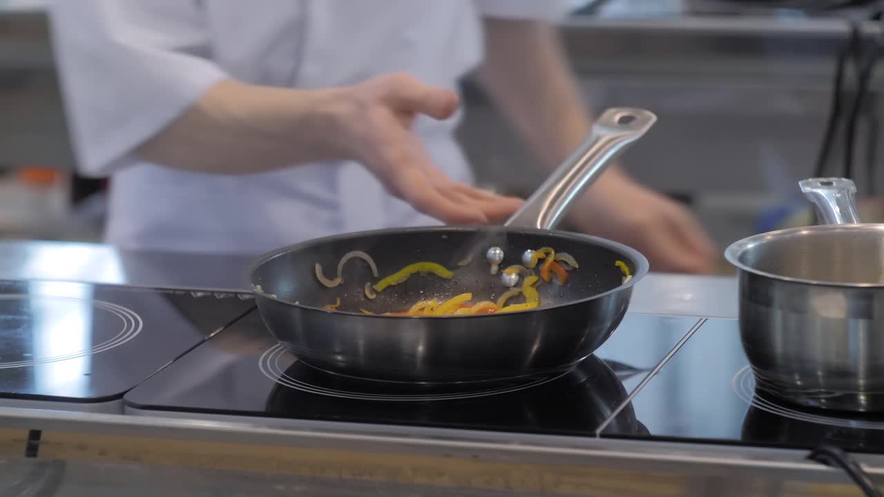 厨师用手在煎锅里烹煮青椒片、洋葱片视频下载