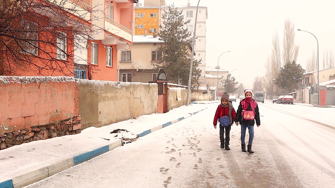 在土耳其的埃尔祖鲁姆，学生们在下雪的时候上学。孩子们玩得很开心。在下雪的城市里散步。背着书包的孩子们。视频下载