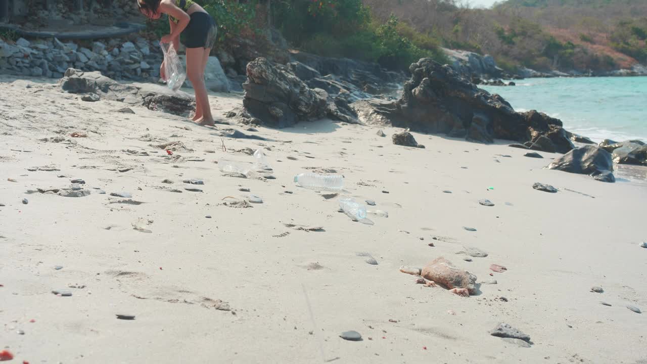 年轻女子在海滩上捡垃圾视频下载