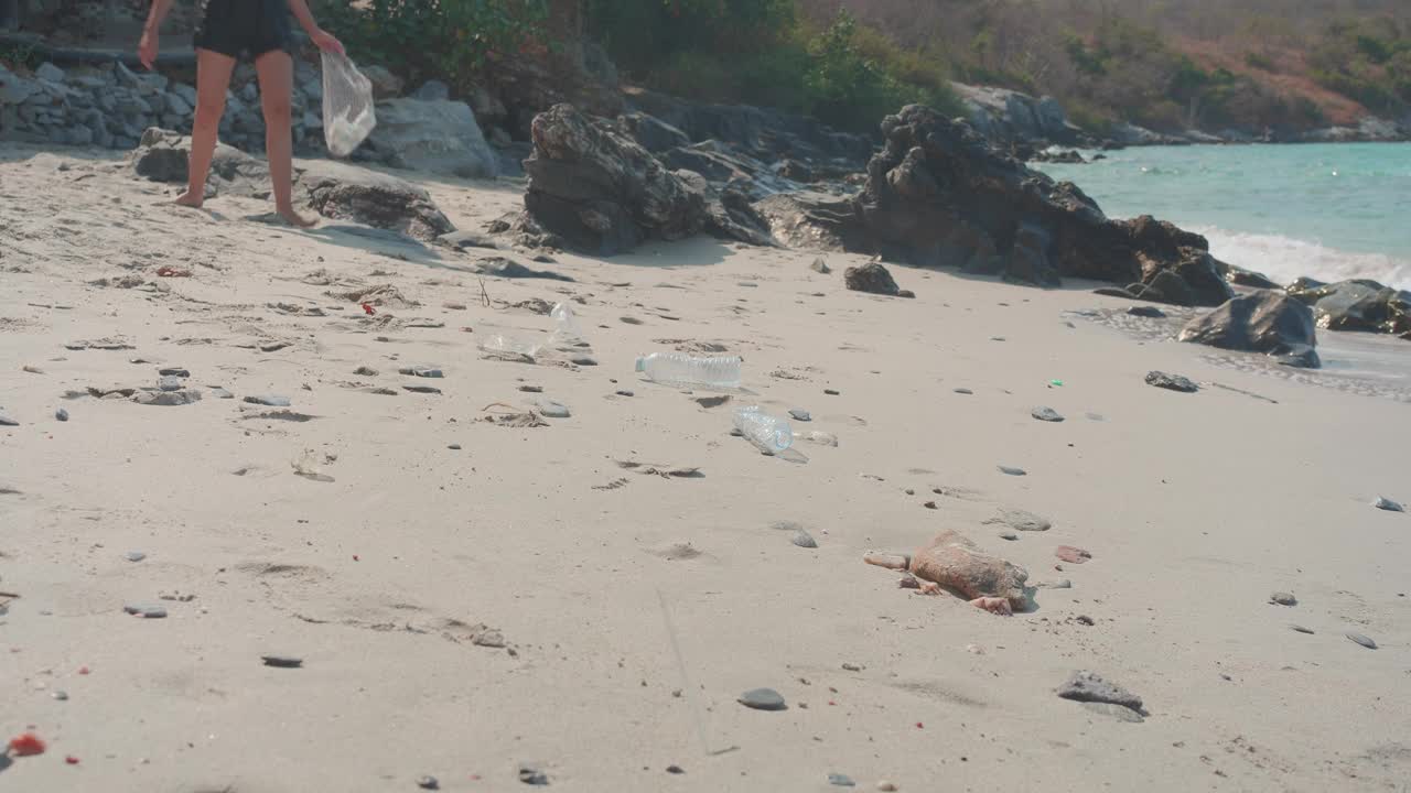 年轻女子在海滩上捡垃圾视频下载