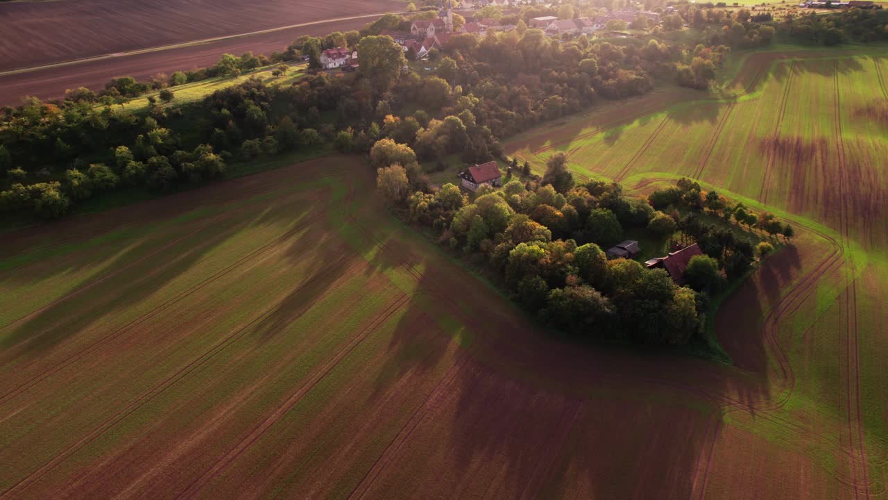 德国一个小村庄秋天的鸟瞰图。田野是黄色和绿色的，太阳正在下山，你可以看到长长的影子视频下载