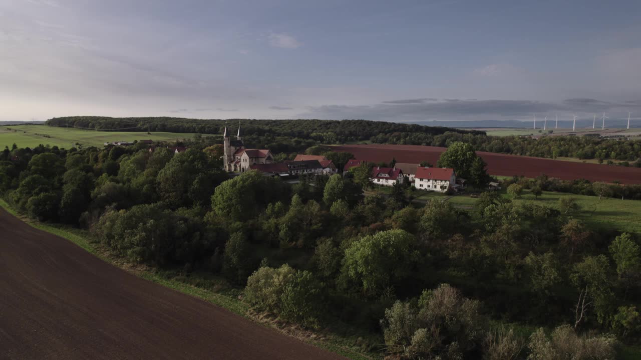秋天，无人机在德国芒chenlochra的一个小村庄上空飞行。田野是黄色和绿色的，太阳正在下山。视频下载