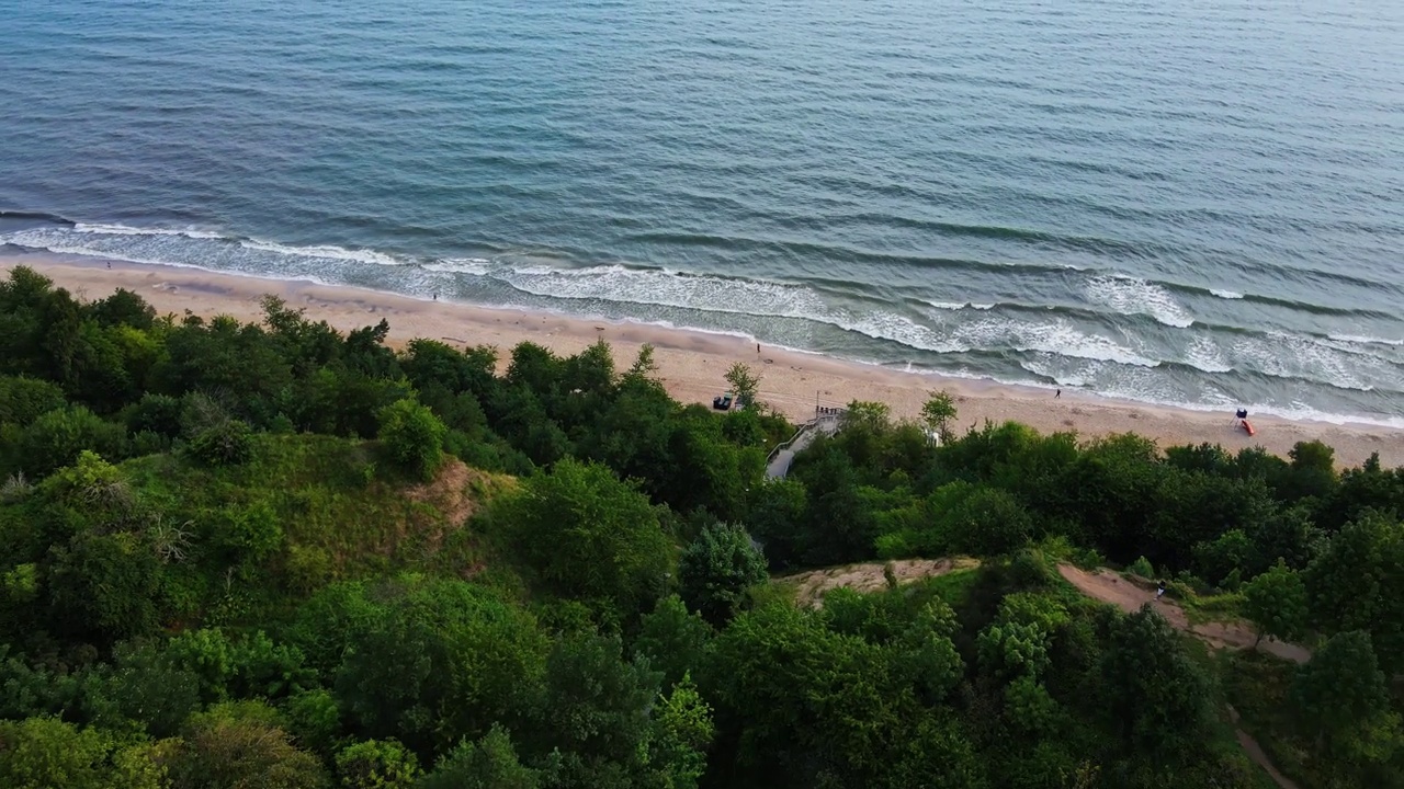 在晴朗的日子鸟瞰Chlapowo海滩与郁郁葱葱的绿色植物视频下载