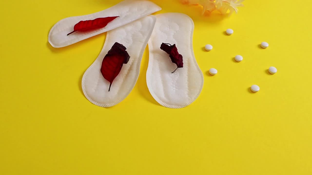 三个女性卫生巾，三片红叶和黄色的药片。视频下载
