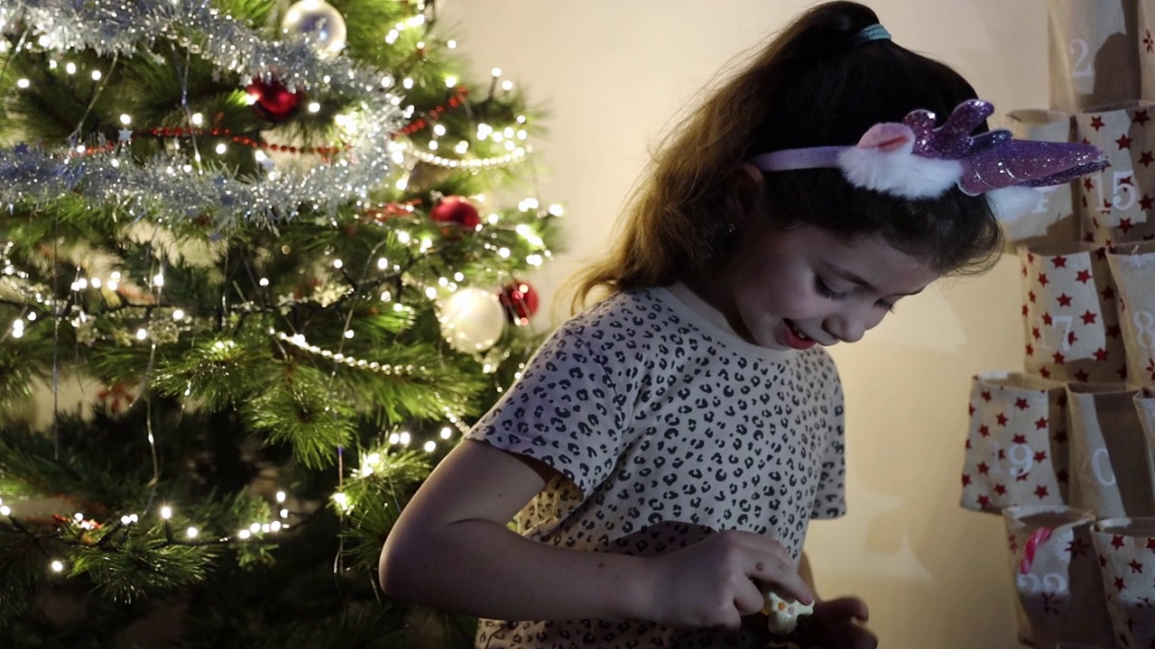 小女孩拿出降临节日历上的圣诞惊喜礼物给大家看。视频下载