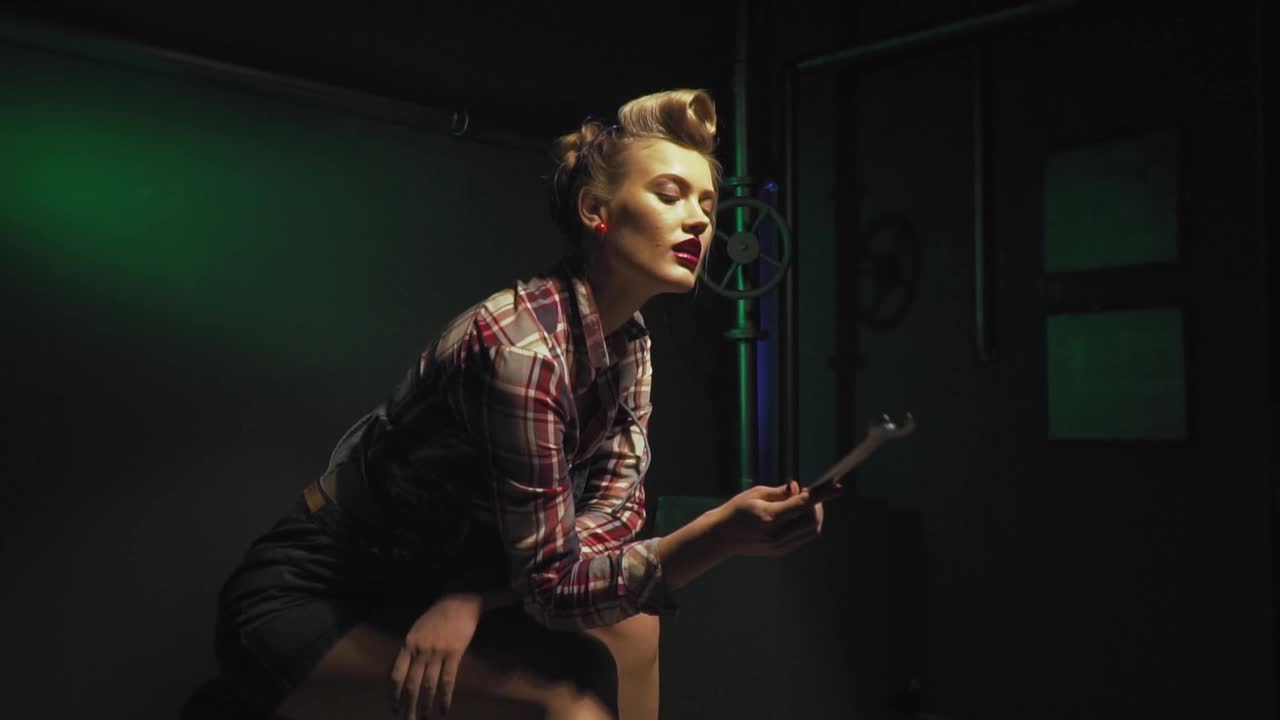 性感的女机械师坐在那里看着扳手，慢动作视频素材