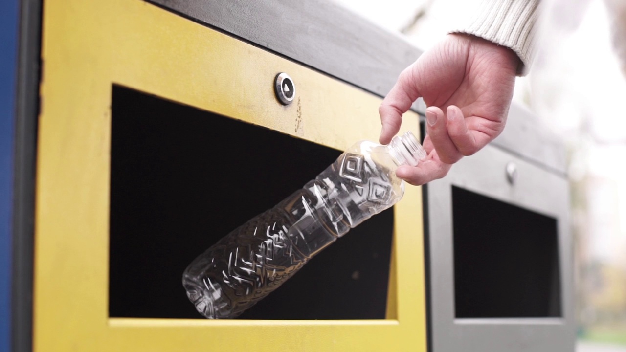一个男人的手扔一个容器，用于回收塑料瓶，垃圾分类，垃圾桶视频下载