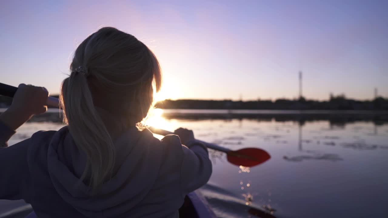 在平静的水面上划桨，在夕阳的背景下，在皮划艇上进行户外活动，水上运动视频下载