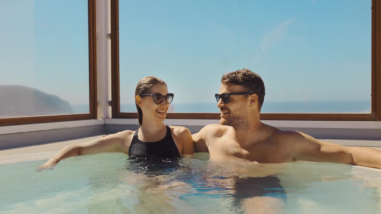 一对夫妇在阳光明媚的日子里在屋顶热水浴缸里放松。暑假，度假旅游视频下载