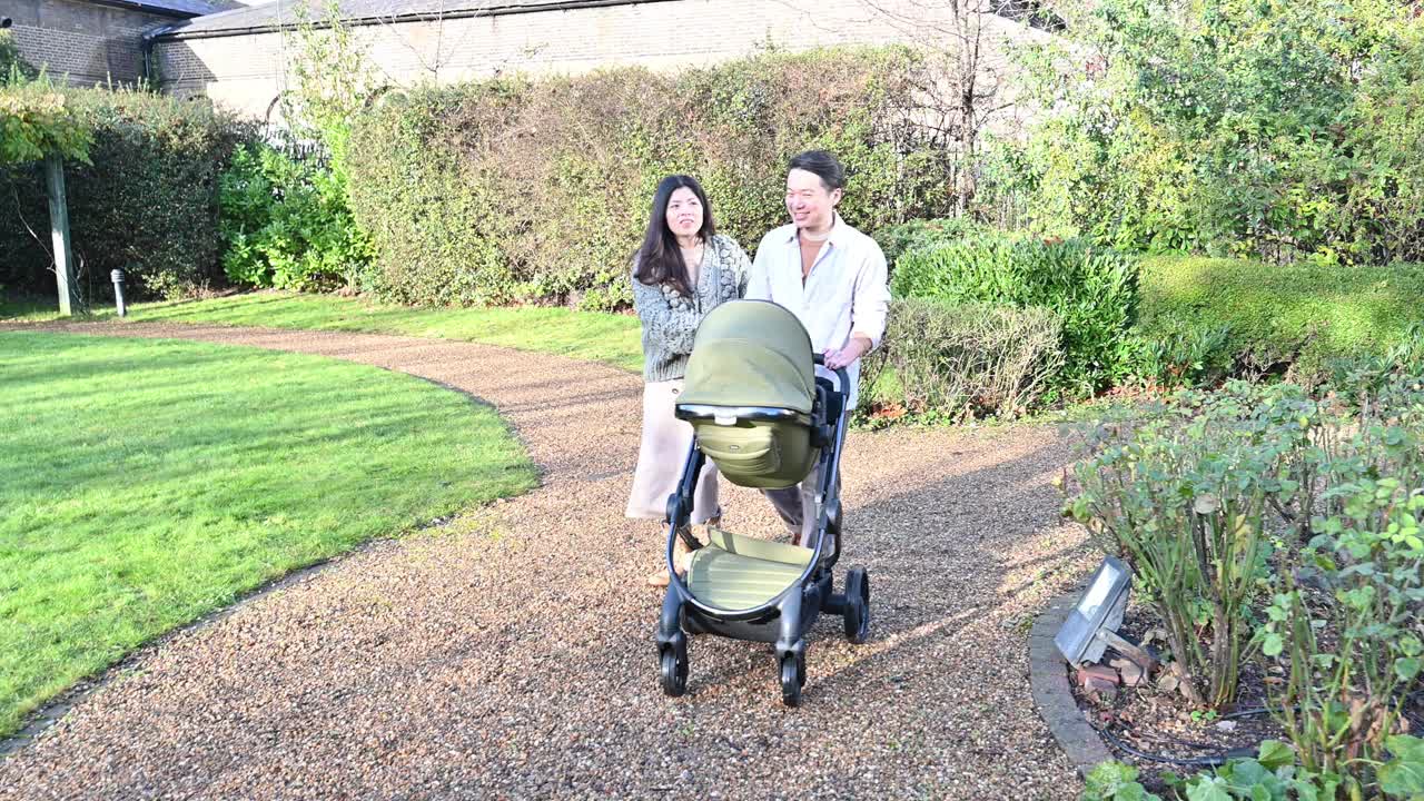 带着孩子在公园散步的亚洲家庭。一对台湾夫妇推着婴儿车，孩子在户外小睡视频素材