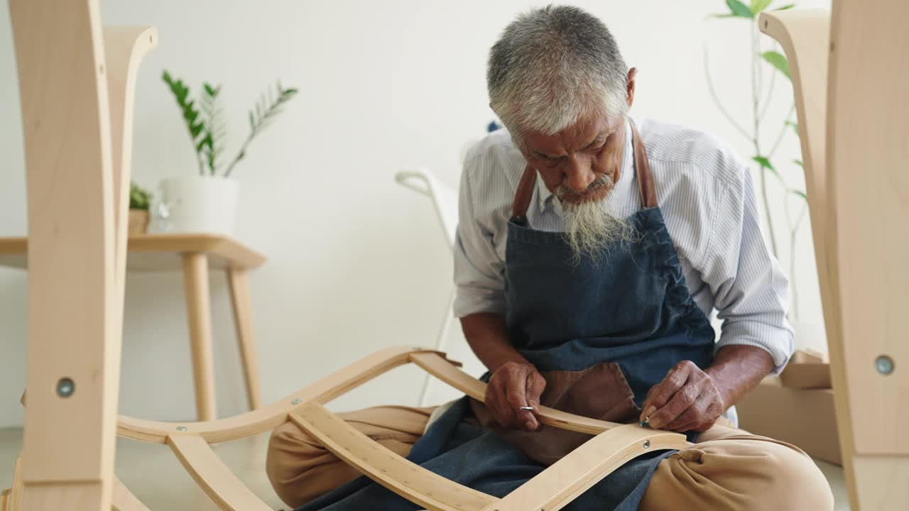 头发灰白的亚洲老人早上在家里组装椅子视频下载
