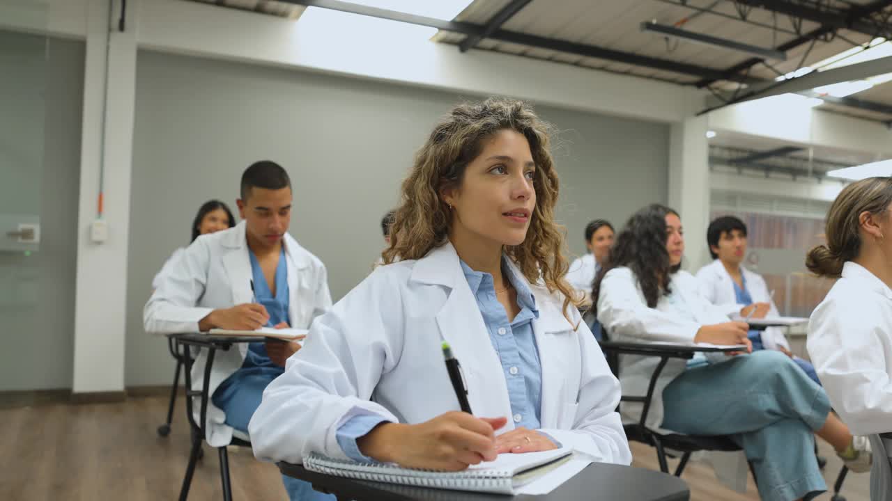 一群拉丁美洲的医科学生坐在教室里听讲座并做笔记视频下载