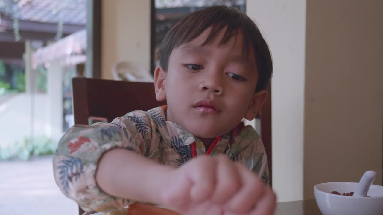 一个小男孩在吃番木瓜。视频下载
