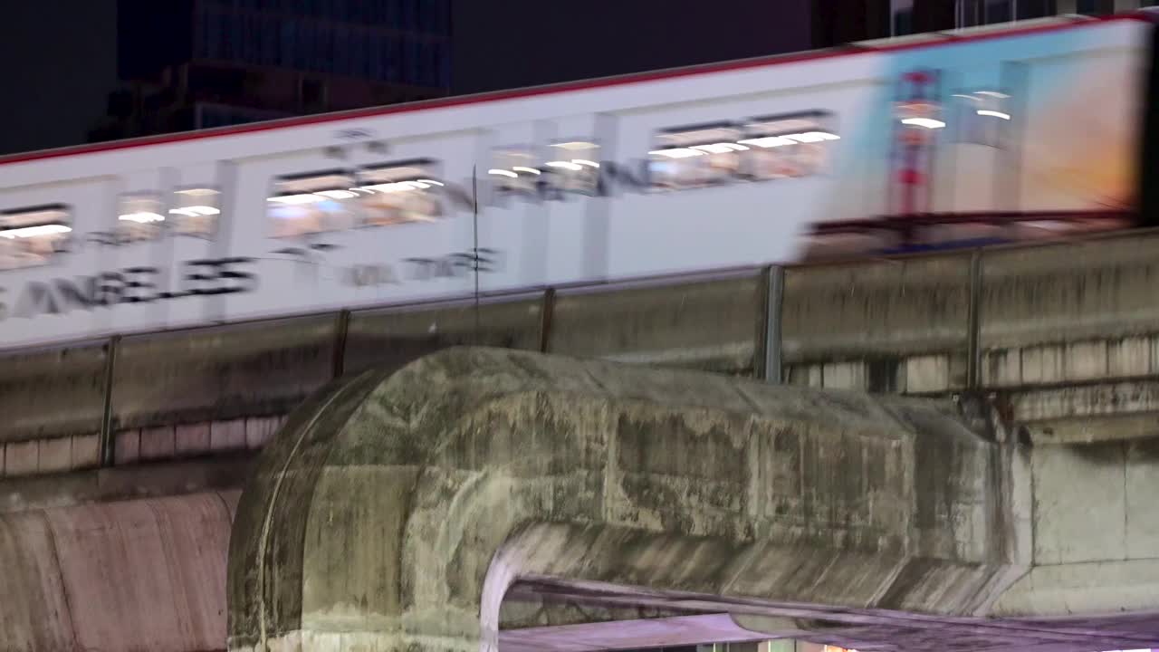 在泰国曼谷，高架轨道上运行的BTS轻轨列车经过一座摩天大楼前视频下载