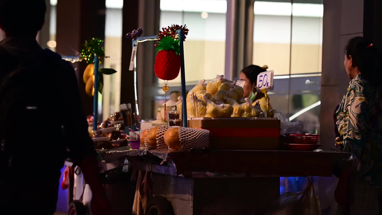 泰国曼谷CBD区的街头小吃摊贩晚上在摊位上卖新鲜的热带水果视频下载