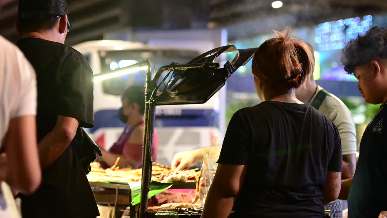 泰国曼谷，一名街头小贩在晚上的摊位上制作烤肉串视频素材