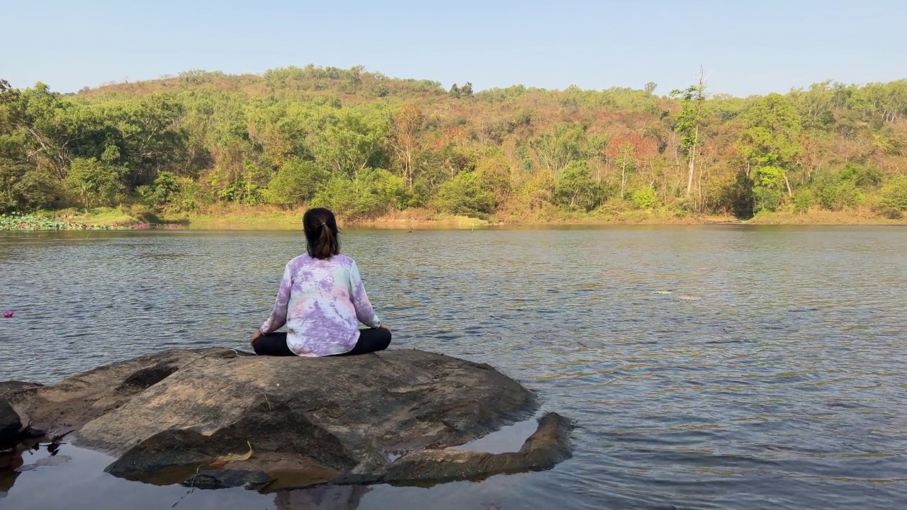 亚洲女性在湖边练习或做瑜伽。视频下载
