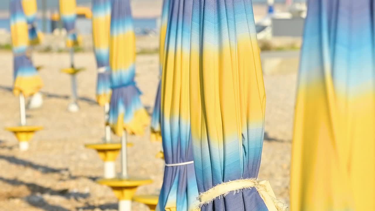 折叠的彩色沙滩遮阳伞在亚得里亚海海岸在阳光明媚的夏日早晨，假日和度假的背景视频下载